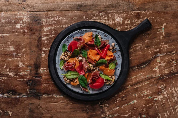 Vista superior de salada saborosa fresca com mexilhões, legumes de raiz e jamon na mesa de madeira — Fotografia de Stock