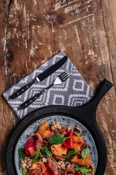 Vue du dessus de la salade avec moules, légumes et confiture sur assiette et fourchette avec couteau sur table en bois — Photo de stock