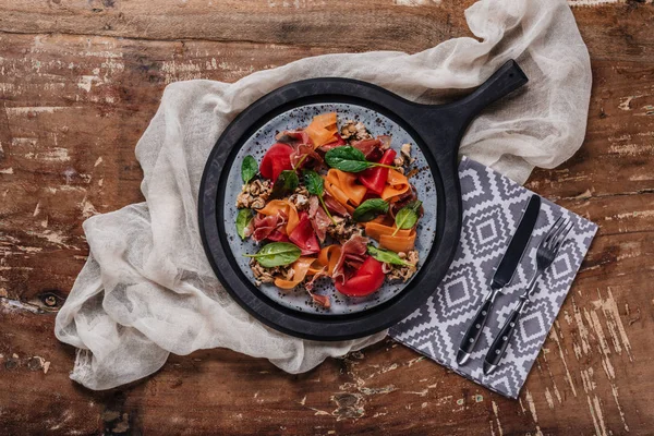 Köstlicher Salat mit Miesmuscheln, Gemüse und Marmelade auf Teller und Gabel mit Messer auf Holztisch — Stockfoto