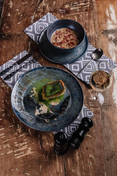 Deliciosa sopa de creme, peixe frito e copo de vinho na mesa de madeira no restaurante — Fotografia de Stock