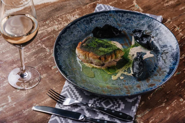 Vista de cerca del delicioso pescado frito y la copa de vino en la mesa de madera - foto de stock