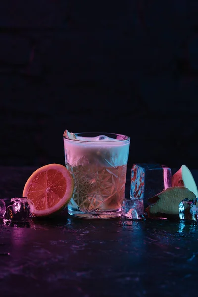 Glas mit Ingwernagel-Cocktail und schmelzenden Eiswürfeln auf dunkler Oberfläche — Stockfoto