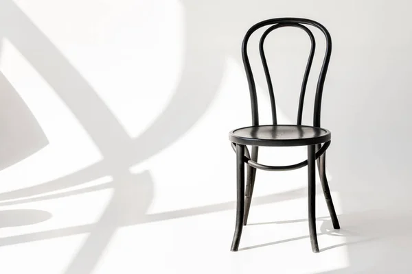 Close up view of black wooden chair on grey backdrop with shadows — Stock Photo