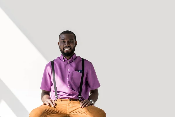 Portrait of smiling african american man in stylish clothing looking at camera on grey background — Stock Photo