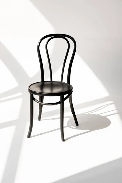 Close up view of black wooden chair on grey backdrop with shadows — Stock Photo