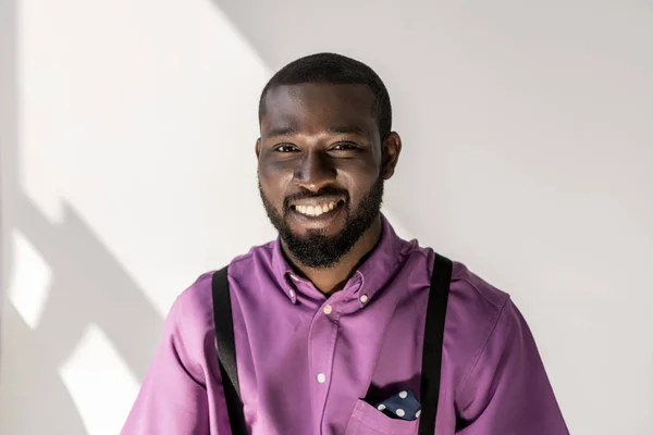 Retrato del hombre guapo afroamericano sonriente mirando a la cámara sobre fondo gris - foto de stock