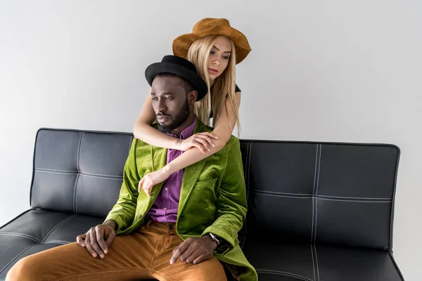 Caucasiano mulher abraçando elegante afro-americano namorado no sofá isolado no cinza — Fotografia de Stock