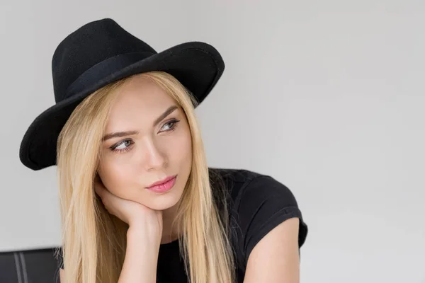 Ritratto di donna attraente pensierosa in cappello nero distogliendo lo sguardo isolato sul grigio — Foto stock