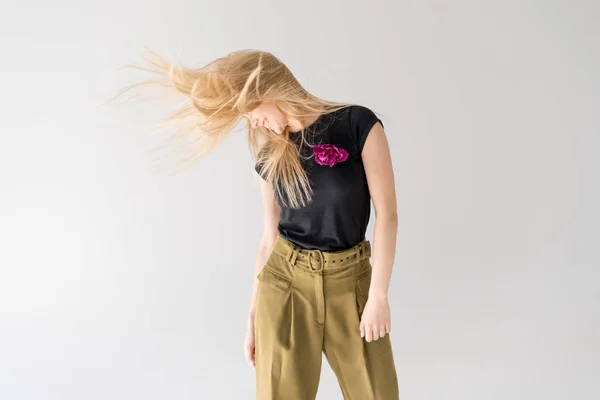 Heureuse jeune femme secouant les cheveux et souriant isolé sur gris — Photo de stock