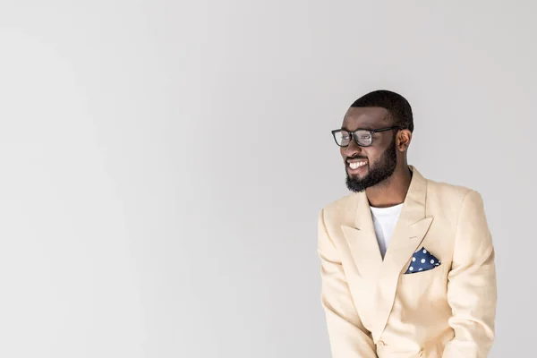 Retrato de joven afroamericano guapo en gafas sonriendo y mirando hacia otro lado aislado en gris - foto de stock