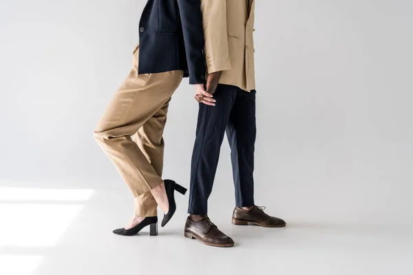 Cropped shot of stylish young multiethnic couple standing back to back and holding hands on grey — Stock Photo