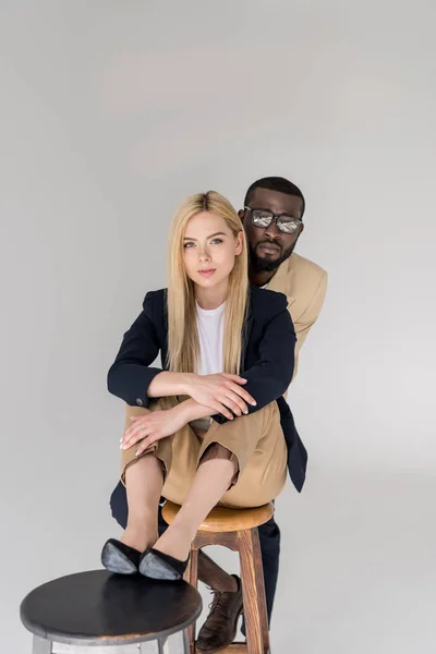 Hermosa elegante joven pareja multiétnica mirando a la cámara aislada en gris - foto de stock