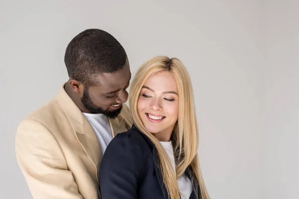 Retrato de belo feliz jovem casal multiétnico posando juntos isolado no cinza — Fotografia de Stock