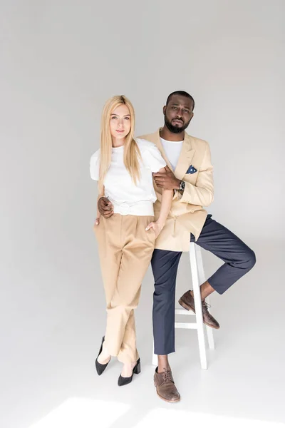 Full length view of stylish young multiethnic couple looking at camera on grey — Stock Photo