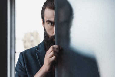 bearded man hiding by frosted glass