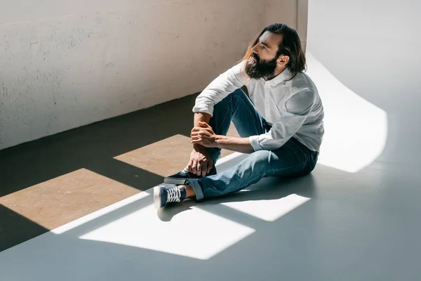 Schöner Mann sitzt auf dem Boden — kostenloses Stockfoto