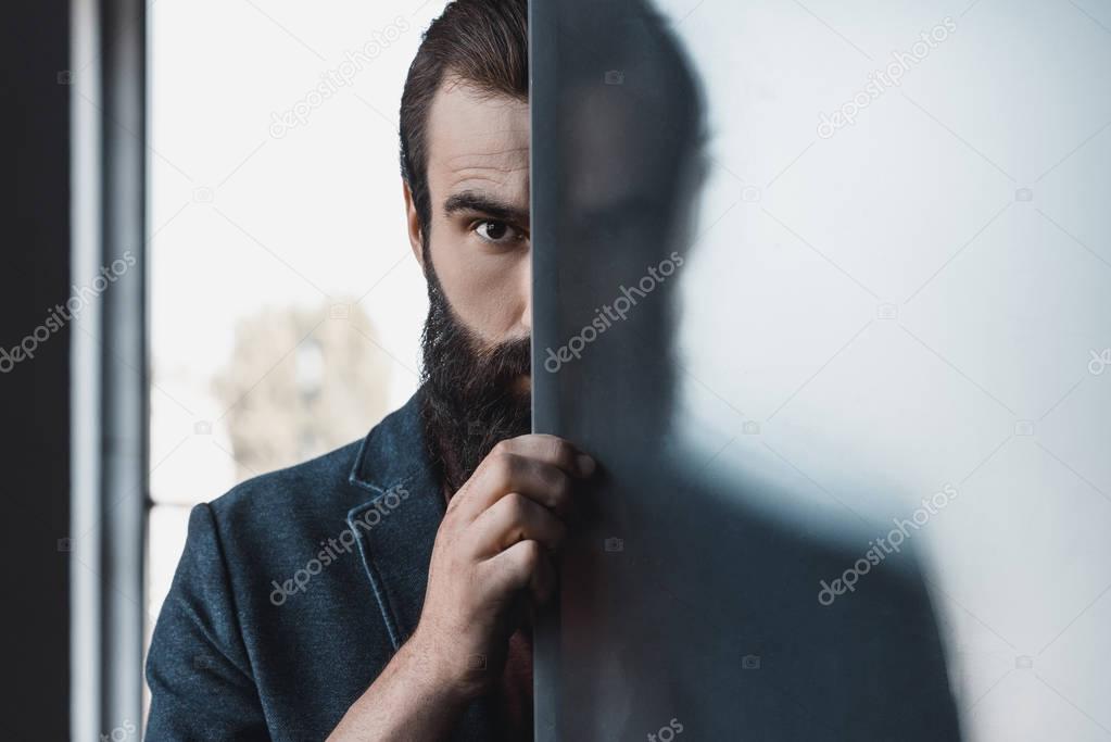 bearded man hiding by frosted glass