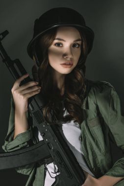 tüfekle, gri gölgeler ile askeri kask içinde güzel beyaz genç kız