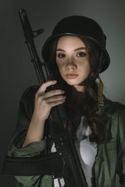 güzel ve genç birbayan tüfeğe, gri gölgeler ile askeri kask içinde