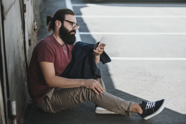Мужчина сидит на полу и пользуется телефоном — стоковое фото