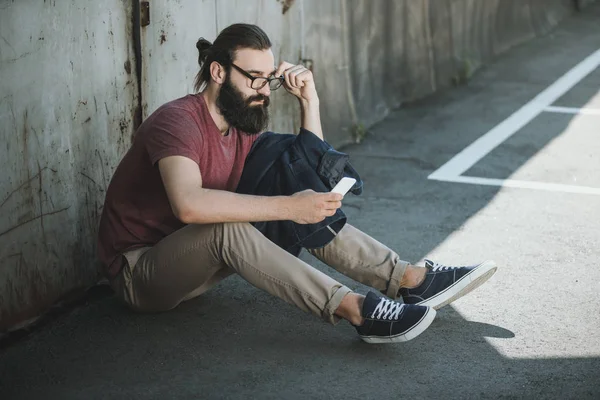Мужчина сидит на полу и пользуется телефоном — стоковое фото