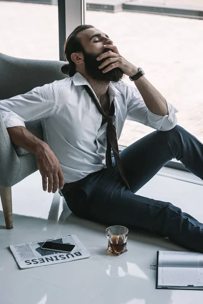 Drunk businessman sitting on floor — Stock Photo