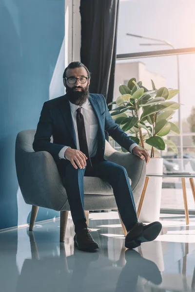 Hombre de negocios barbudo sentado en sillón - foto de stock