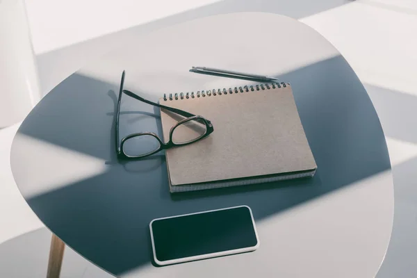 Smartphone, notepad and eyeglasses — Stock Photo