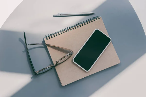 Smartphone, notepad and eyeglasses — Stock Photo
