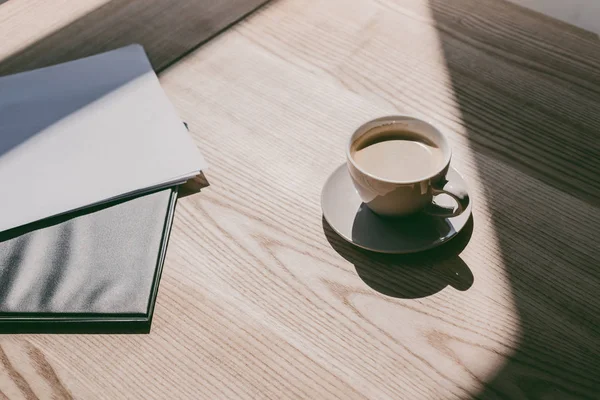 Taza de café y cuadernos en la mesa - foto de stock