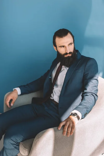 Hombre de negocios barbudo sentado en sillón - foto de stock