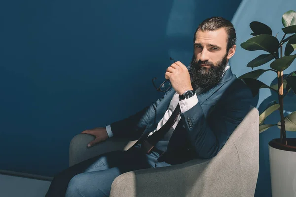 Hombre de negocios barbudo sentado en sillón - foto de stock
