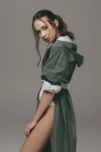 Beautiful stylish girl posing in green raincoat, isolated on grey — Stock Photo