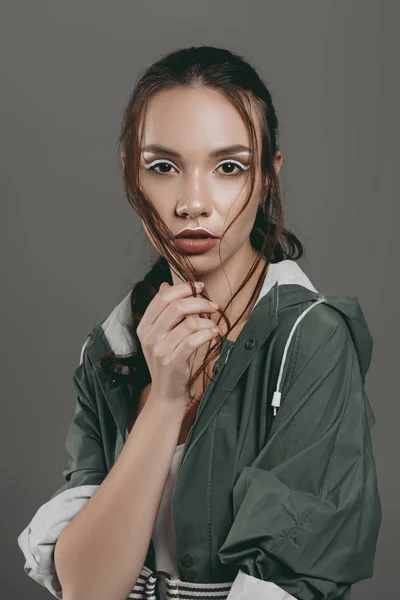 Attraktives Mädchen mit Make-up posiert im trendigen Regenmantel, isoliert auf grau — Stockfoto