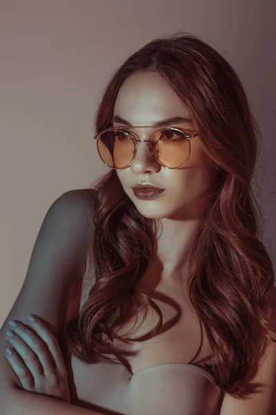 Attractive girl posing in yellow sunglasses, isolated on grey — Stock Photo