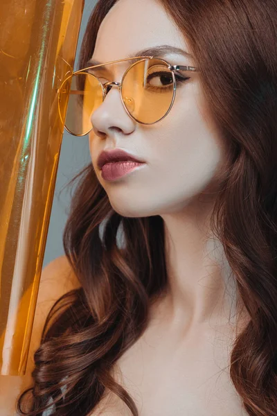 Schöne sinnliche Mädchen posiert mit gelben Sonnenbrillen, isoliert auf grau — Stockfoto