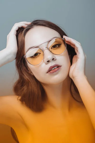 Sinnliches Mädchen posiert mit gelber Sonnenbrille, isoliert auf grau — Stockfoto