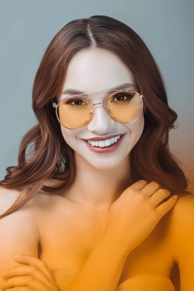 Cheerful girl posing in yellow sunglasses, isolated on grey — Stock Photo