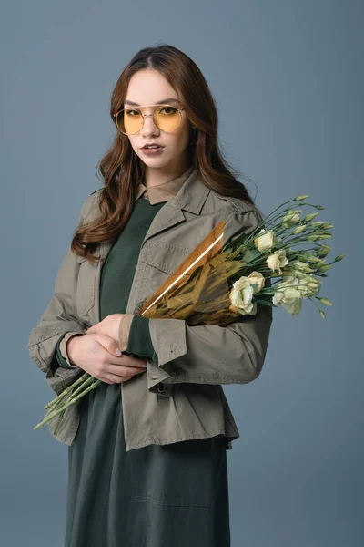 Fille à la mode posant en tenue d'automne avec bouquet de fleurs, isolé sur gris — Photo de stock