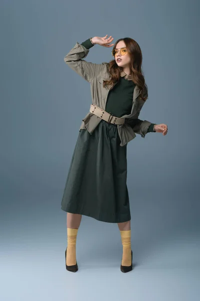 Привлекательная стильная девушка, позирующая в модном осеннем наряде, изолированная на сером — стоковое фото