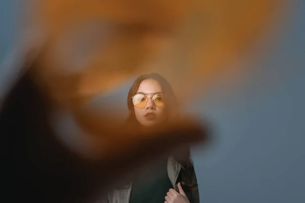 Fille à la mode posant en tenue d'automne et lunettes de soleil jaunes, isolé sur gris avec filtre orange — Photo de stock