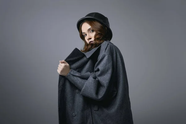 Fashionable model posing in autumn coat and military helmet, isolated on grey — Stock Photo