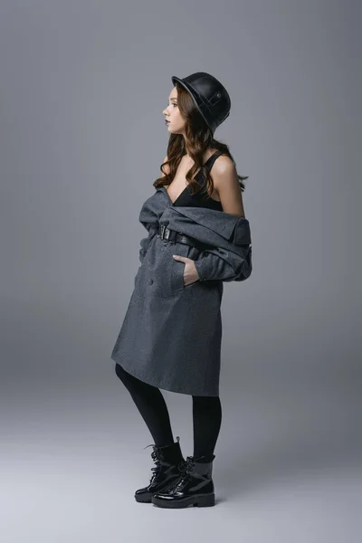 Stylish beautiful girl posing in autumn coat and military helmet, isolated on grey — Stock Photo