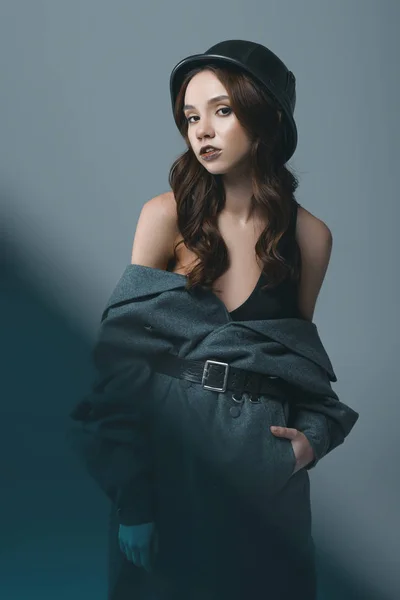 Menina elegante posando em casaco de outono e capacete militar, isolado em cinza com filtro azul — Fotografia de Stock