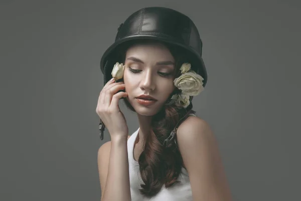 Привлекательная молодая девушка в военном шлеме с белыми цветами, изолированная на сером — стоковое фото