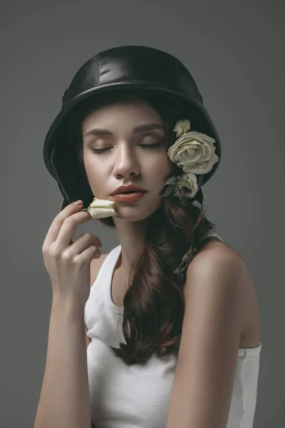 Tender young girl with closed eyes in military helmet with white flowers, isolated on grey — Stock Photo