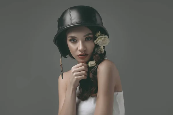 Hermosa joven en casco militar con flores blancas, aislado en gris - foto de stock