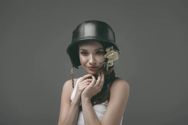 Beautiful young woman in military helmet with flowers, isolated on grey — Stock Photo