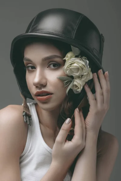 Нежная девушка в военном шлеме с цветами, изолированные на сером — стоковое фото