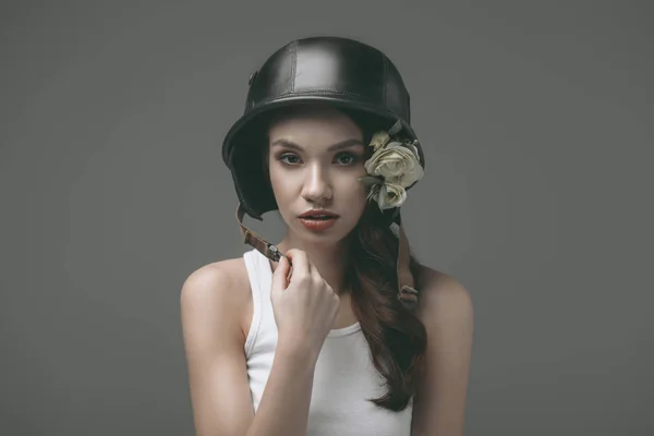 Tender young woman in military helmet with flowers, isolated on grey — Stock Photo